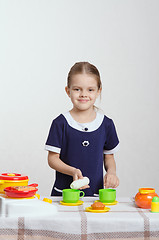 Image showing Girl pouring milk a cup in the kitchen