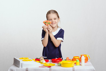 Image showing Girl with a slice of pizza on children's kitchen