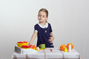 Image showing Girl hostess putting the pan on stove