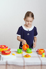 Image showing Girl pouring milk into a cup of children's kitchen