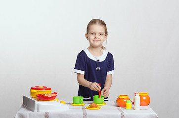 Image showing Girl with a spoon in cup prevents children's kitchen