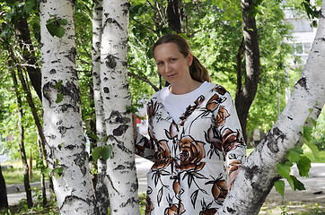 Image showing The happy woman stands near birches in park.