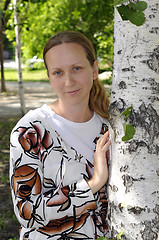 Image showing The happy woman stands near birches in park.