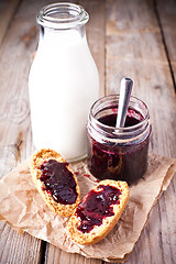 Image showing black currant jam in glass jar, milk and crackers 