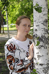 Image showing The happy woman stands near birches in park.