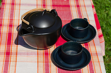 Image showing black ceramic tea set on checked background 