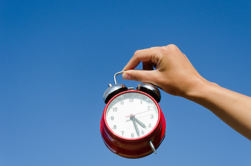 Image showing hand hold chrome alarmclock on blue sky abckground 