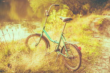 Image showing Little green bicycle standing on green summer meadow