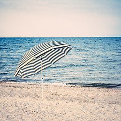Image showing Striped umbrella on sandy beach