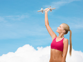 Image showing smiling woman with heavy steel dumbbell