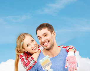 Image showing smiling couple covered with paint with paint brush