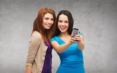Image showing two smiling teenagers with smartphone