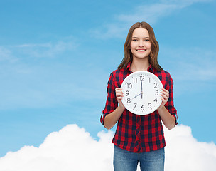 Image showing young woman in casual clothes with wall clock