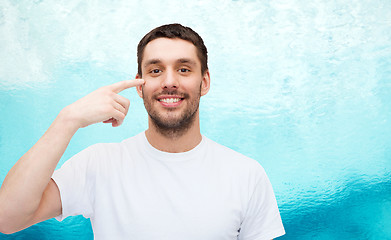 Image showing smiling young handsome man pointing to eyes