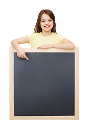 Image showing happy little girl pointing finger to blackboard