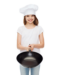 Image showing smiling girl in cook hat giving frying pan