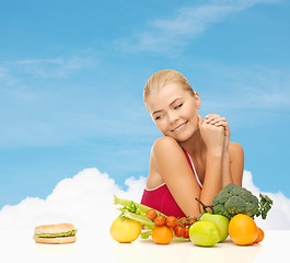 Image showing doubting woman with fruits and hamburger