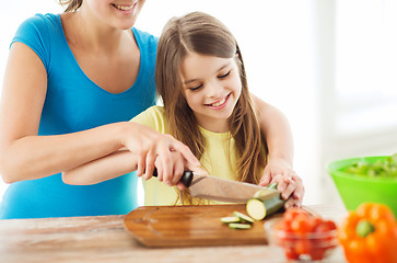 Image showing smiling little girl with mother chopping cucumber