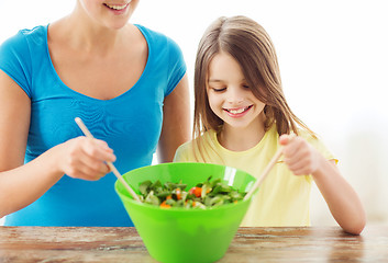 Image showing little girl with mother mixing salad in kitchen