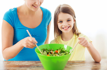 Image showing little girl with mother mixing salad in kitchen