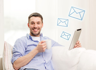 Image showing smiling man working with tablet pc at home