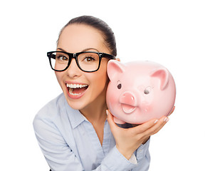 Image showing happy businesswoman in eyeglasses with piggy bank