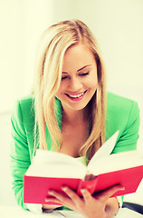 Image showing smiling young woman reading book at school