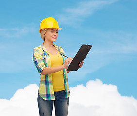 Image showing smiling woman in helmet with clipboard