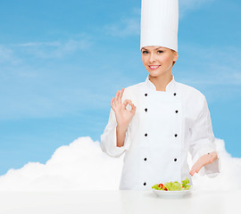 Image showing smiling female chef with salad on plate