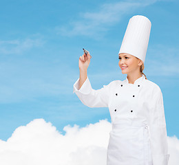 Image showing smiling female chef writing something on air