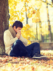 Image showing ill man with paper tissue in autumn park