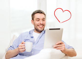 Image showing smiling man working with tablet pc at home