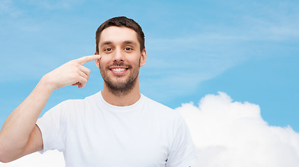 Image showing smiling young handsome man pointing to eyes