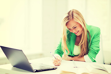 Image showing smiling student girl writing in notebook