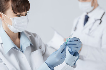 Image showing female doctor holding syringe with injection