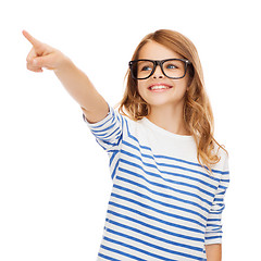 Image showing cute little girl in eyeglasses pointing in the air