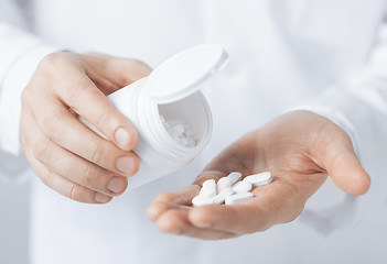 Image showing doctor hands holding white pack and pills