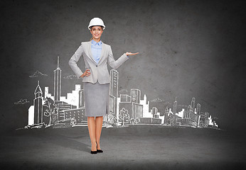 Image showing businesswoman in helmet holding something on palm