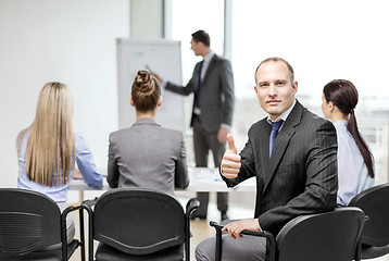 Image showing businessman with team showing thumbs up in office