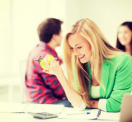 Image showing smiling student girl eating apple at school