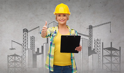 Image showing smiling woman in helmet with clipboard