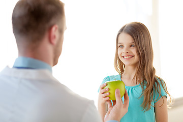 Image showing male doctor giving an apple to smiling little girl