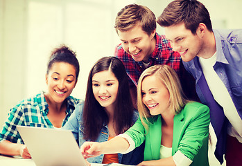 Image showing smiling students looking at laptop at school