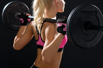 Image showing sporty woman exercising with barbell from back