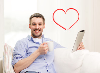 Image showing smiling man working with tablet pc at home