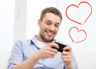 Image showing smiling man with smartphone at home