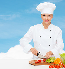 Image showing smiling female chef chopping vegetables