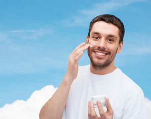 Image showing beautiful smiling man applyin cream