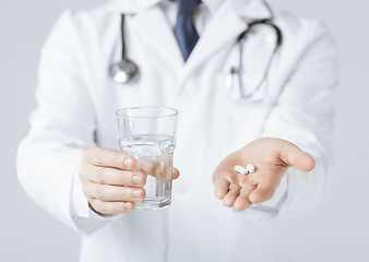 Image showing doctor hands giving white pills and glass of water