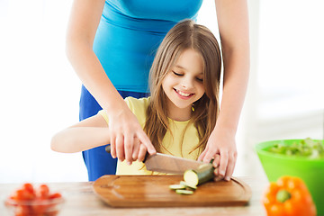 Image showing smiling little girl with mother chopping cucumber